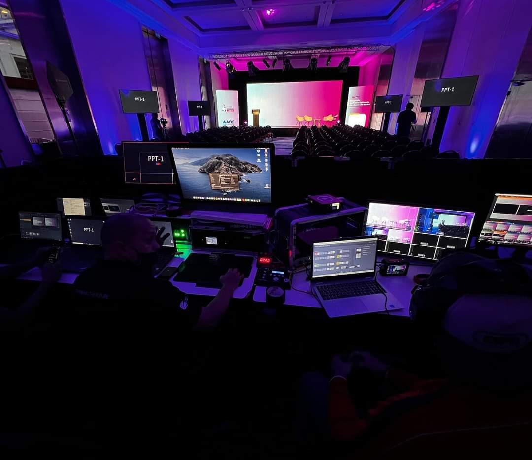 Control room técnico con múltiples monitores operando evento en vivo con pantalla LED e iluminación