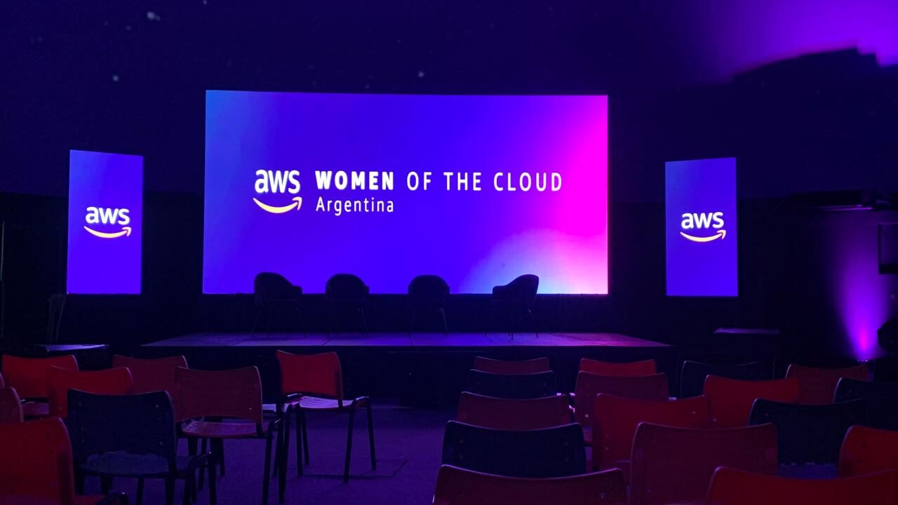 AWS Women of the Cloud Argentina con triple pantalla LED y iluminación violeta